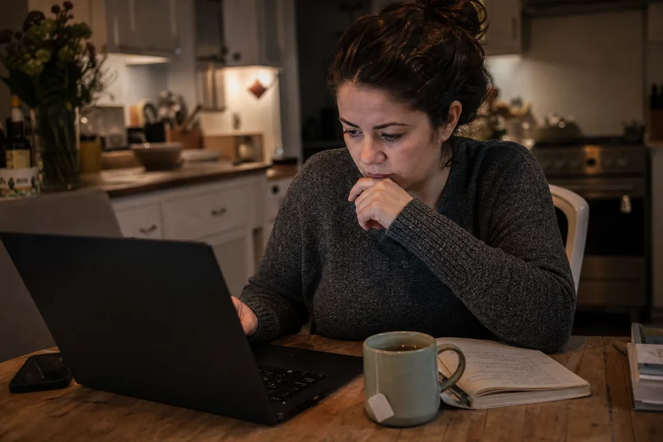 A searcher reading an online community forum for business buyers on a laptop at a kitchen table at night